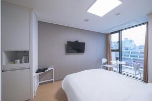 チュンチョンにあるChuncheon Bella Residenceの白いベッドと窓が備わるホテルルームです。