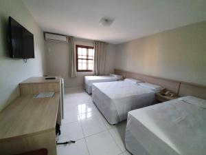 um quarto de hotel com duas camas e uma televisão em Apartamento Porto Bello Park by Decolando Turismo em Porto Seguro