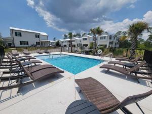a pool with chaise lounge chairs and a swimming pool at 5 Star 4/3 sleeps 16 with Arcade GAME ROOM & POOL! in Orange Beach