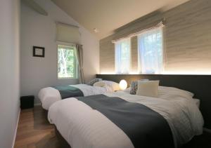 - 3 lits dans une chambre avec 2 fenêtres dans l'établissement GREEN SEED Karuizawa, à Karuizawa
