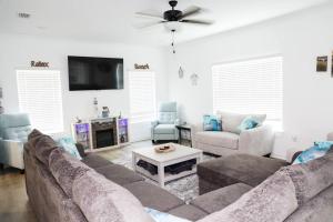 a living room with a couch and a tv at 5 Star 4/3 sleeps 16 with Arcade GAME ROOM & POOL! in Orange Beach