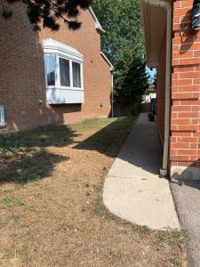 a brick house with a sidewalk next to a building at Relaxing 3 Bedroom Basement Stay in Mississauga