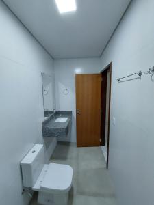 y baño con aseo, lavabo y espejo. en Linda casa na cidade de Chapada dos Guimarães/MT., en Chapada dos Guimarães