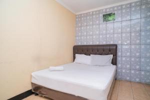 ein kleines Schlafzimmer mit einem Bett mit weißer Bettwäsche in der Unterkunft Sabar Mansion 22 Mitra RedDoorz in Jakarta
