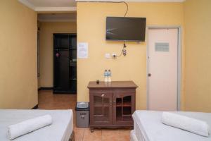 Zimmer mit 2 Betten und einem TV an der Wand in der Unterkunft Sabar Mansion 22 Mitra RedDoorz in Jakarta