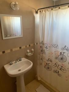 a bathroom with a sink and a shower curtain with bicycles on it at Casita en plottier in Plottier