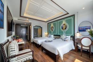 Habitación de hotel con 2 camas, mesa y sillas en Le Pavillon Hoi An Gallery Hotel & Spa en Hoi An