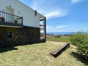 ein Haus mit einem Balkon und einer Bank im Gras in der Unterkunft casa panorâmica bela vista in Angra do Heroísmo