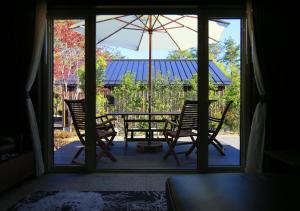 une terrasse avec une table, des chaises et un parasol dans l'établissement GREEN SEED Karuizawa, à Karuizawa
