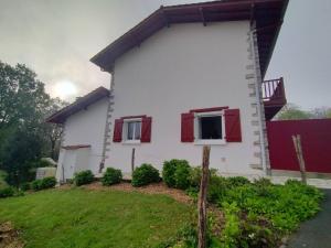 a white house with red windows and a yard at Appartement T3 confortable avec terrasse, 2 chambres, cuisine équipée, Wi-Fi – Larressore - FR-1-495-122 in Larressore
