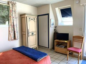 a bedroom with a bed and a desk and a television at Maison Pleumeur-Bodou, 1 pièce, 4 personnes - FR-1-368-395 in Pleumeur-Bodou