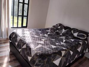 un letto con piumone bianco e nero in una stanza di Cabaña la Rivera a Nemocón