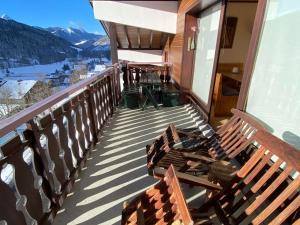 einen Balkon mit zwei Holzbänken auf einem Haus in der Unterkunft Spacieux appartement 2 chambres avec balcon ensoleillé - FR-1-692-82 in La Chapelle-dʼAbondance