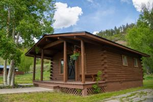 a small cabin with a porch in the grass at High Creek Lodge and Cabins in Pagosa Springs