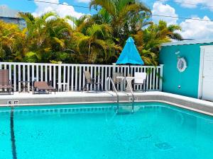 a swimming pool with chairs and a blue house at Cottage Bungalow Near Beach! 1 Bed with Pool & BBQ in Fort Myers