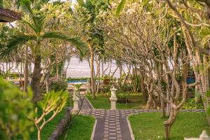 a walkway through a park with trees and the ocean at Coral Bay Bungalows Amed Bali in Amed