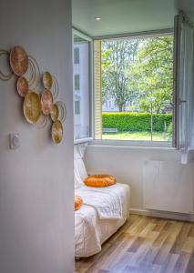 Schlafzimmer mit einem Fenster und einem Bett mit orangefarbenen Kissen in der Unterkunft Le Taillefer 4 - L'Oasis in Rhut