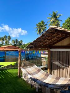 a hammock on a patio with a view of the ocean at Suítes Naldiane in Imbassai