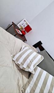 a bed with a pillow and a table with a book at Departamento Vela Céntrico in Concepción