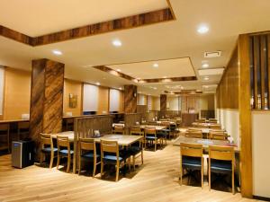 ​Hotel Route-Inn Kumagaya​ في كوماغايا: غرفة طعام مع طاولات وكراسي خشبية