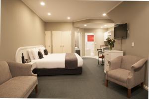 a hotel room with a bed and two chairs at Cornwall Motor Lodge in Palmerston North