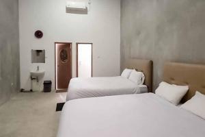 um quarto de hotel com duas camas e uma casa de banho em Sukawana Guest House Mitra RedDoorz 
