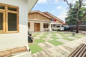 una casa con suelo verde a cuadros frente a un edificio en Sukawana Guest House Mitra RedDoorz, 