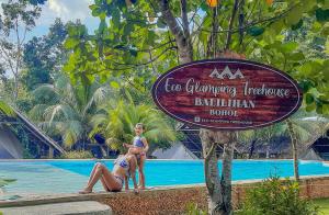 two women standing next to a swimming pool at a resort at Eco Glamping Treehouses Closest Resort To All Tourist Attractions in Balilihan