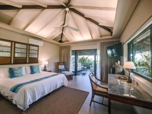 a bedroom with a bed and a table with a ceiling at Kaimana Resort Siargao in General Luna