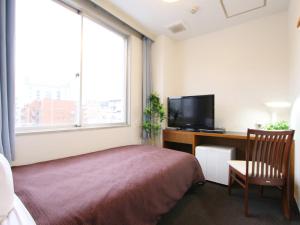 a bedroom with a bed and a desk with a television at HOTEL LiVEMAX BUDGET Tokyo Kiba in Tokyo