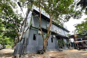 un edificio con un árbol delante de él en Rumah Ceria near Bandara Ahmad Yani Semarang RedPartner en Kalibanteng-lor