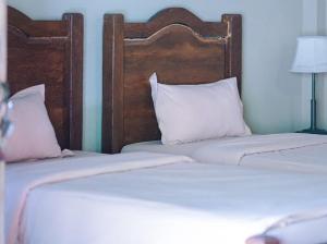two twin beds with white pillows in a bedroom at Rumah Dharma 2 Riverside in Borobudur