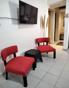 two red chairs and a tv on a wall at C & J Casa de alquiler in Maco
