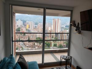 a living room with a large window with a view of a city at shared -compartido- apartment in a quiet, secure and lovely apartment in Sabaneta