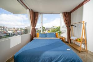 a bedroom with a blue bed and a large window at Raon Dalat - STAY 24H in Da Lat