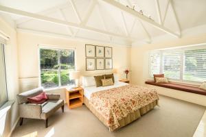 a bedroom with a bed and a chair and windows at Cape Lodge in Yallingup