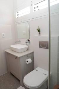 Gorgeous 1-bedroom Sandton flat في جوهانسبرغ: حمام ابيض مع مرحاض ومغسلة