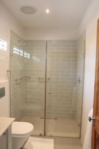 a bathroom with a glass shower with a toilet at Gorgeous 1-bedroom Sandton flat in Johannesburg