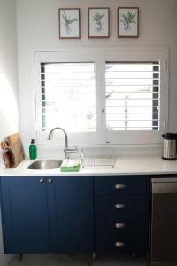 kuchnia z niebieskimi szafkami i umywalką oraz 2 oknami w obiekcie Gorgeous 1-bedroom Sandton flat w mieście Johannesburg