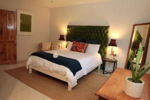 a bedroom with a large bed with a green headboard at Gorgeous 1-bedroom Sandton flat in Johannesburg