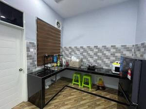 マランにあるHomestay 4Sのキッチン(黒いカウンター、緑のスツール2脚付)