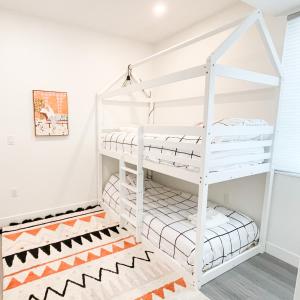 ein weißes Etagenbett in einem weißen Zimmer mit einem Teppich in der Unterkunft *NEW* HAVN HOUSE MODERN RETREAT - STEPS FROM BEACH in Penticton