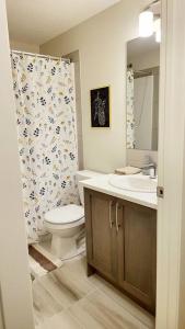 een badkamer met een toilet, een wastafel en een douche bij The Oliver - Cozy Apartment in Rockland Park, NW in Calgary