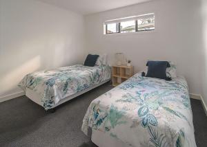 a bedroom with two beds and a small table at Summerhouse Pet Friendly at Surf Beach in Surf Beach