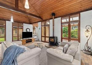 a living room with two white couches and a tv at Sand at Broulee in Broulee