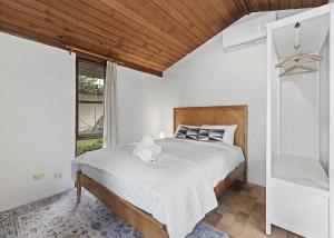 a bedroom with a large bed with a large window at Sand at Broulee in Broulee