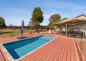 a swimming pool on a wooden deck with an umbrella at Marie's Rest in Tomakin