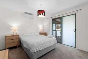 a bedroom with a bed and a large glass door at Teds at Broulee in Broulee