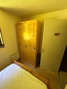 a bedroom with a bed and a wooden cabinet at Superbe appartement tout équiper in Lélex