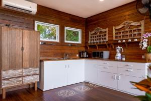 a kitchen with white cabinets and wooden walls at Villa Atra Bambulogy by Nagisa Bali in Kerobokan
